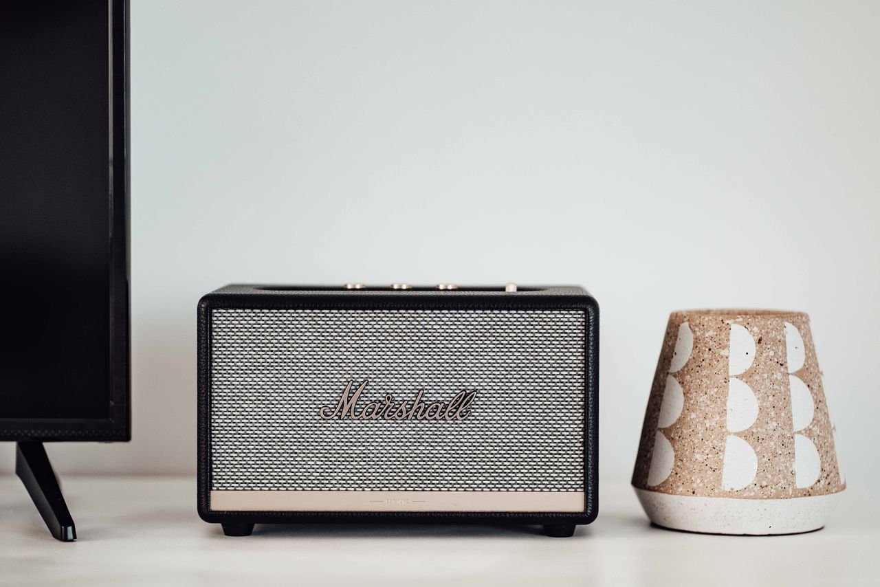 Marshall Bluetooth speaker alongside a ceramic holder on a modern table setup.