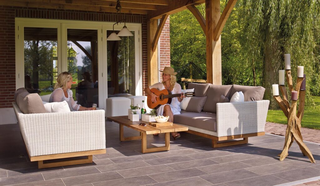 collection-03 Two women enjoying a serene patio scene with a guitar and candles, surrounded by greenery.