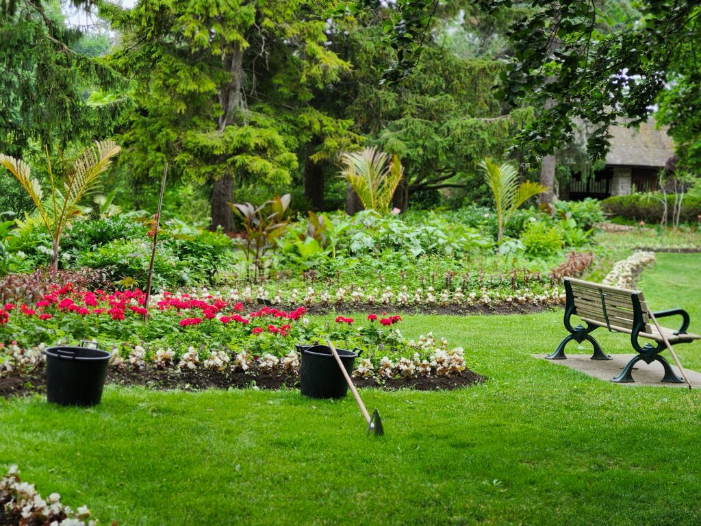 collection-05 Tranquil park scene featuring lush greenery, a flower garden, and an empty bench.